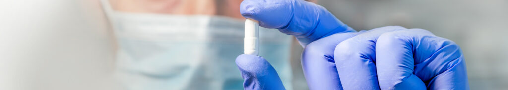 Panoramic web banner female medical or research scientist or doctor using looking at a test tube of clear solution in a lab or laboratory. Header panorama.